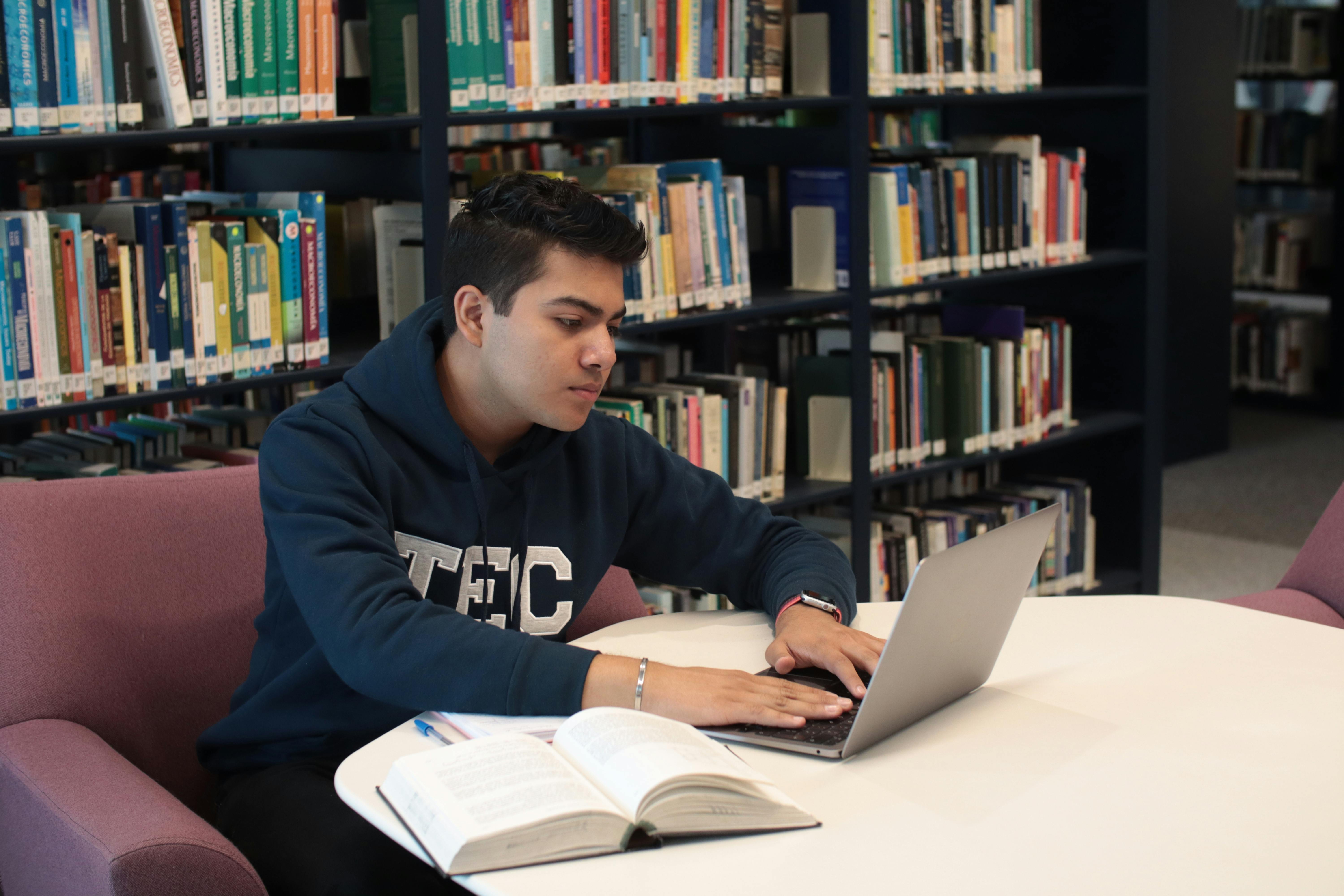 Student using a MacBook in a library setting
