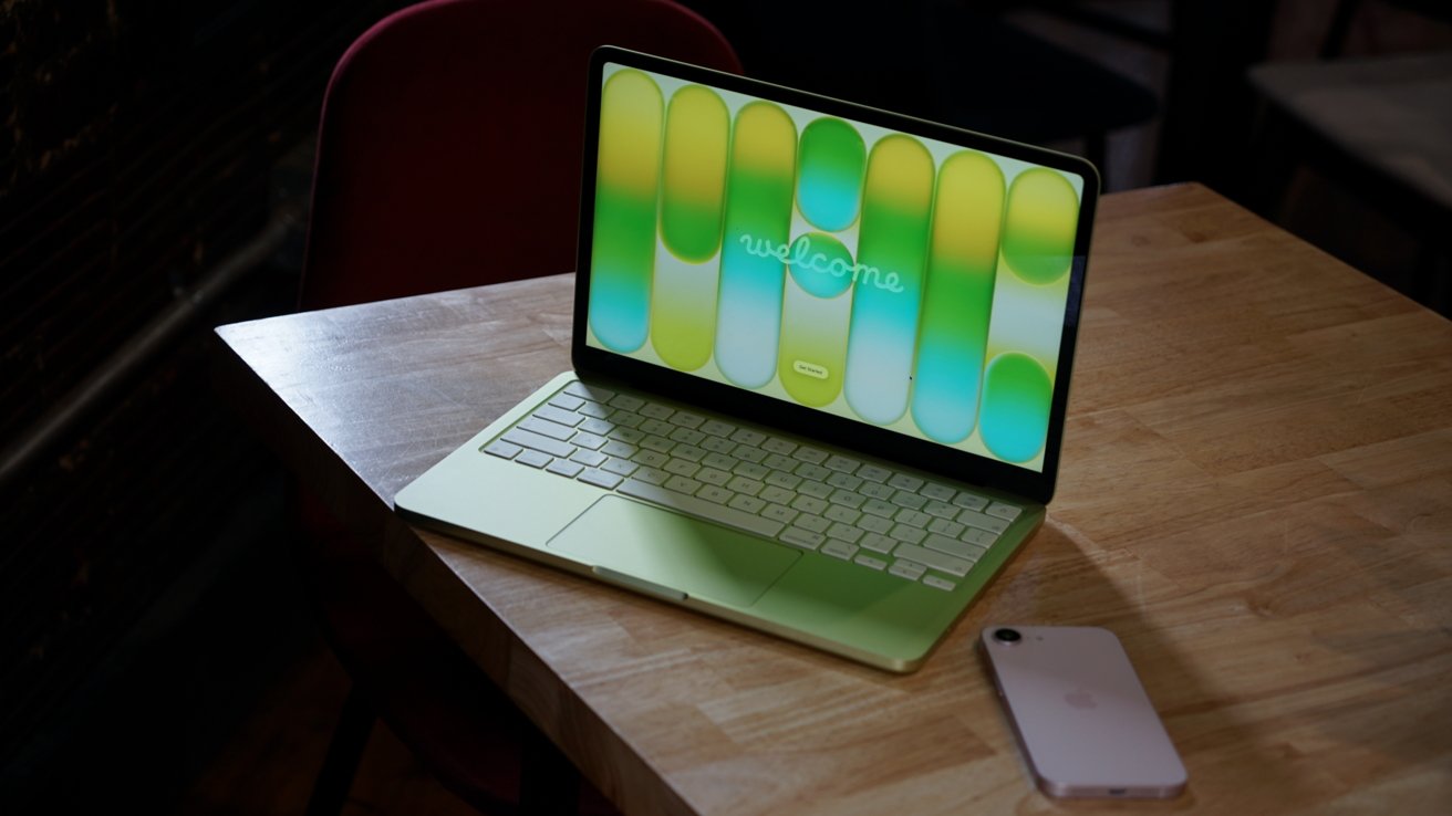 MacBook Neo laptop open on a desk showing its screen and keyboard